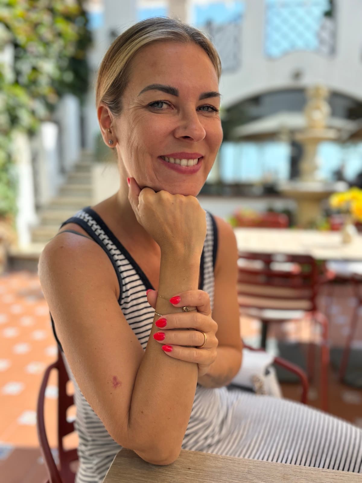 Katja lächelnd auf einer sonnigen Terrasse